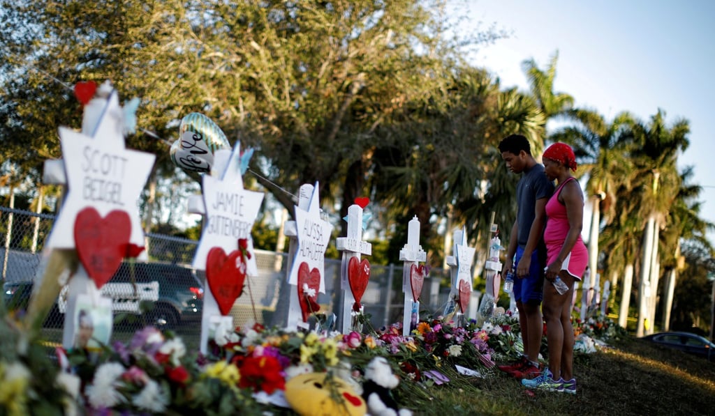 Adin Chistian, 16, student of the Marjory Stoneman Douglas High School, and his mother Denyse, look at the crosses and Stars of David placed to commemorate those killed in the Parkland, Florida, mass shooting. Photo: Reuters