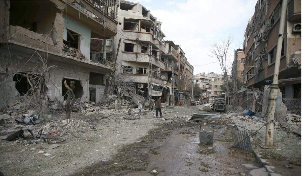 People walk through the damage after an air raid in the besieged town of Douma, Eastern Ghouta, on Friday. Photo: Reuters