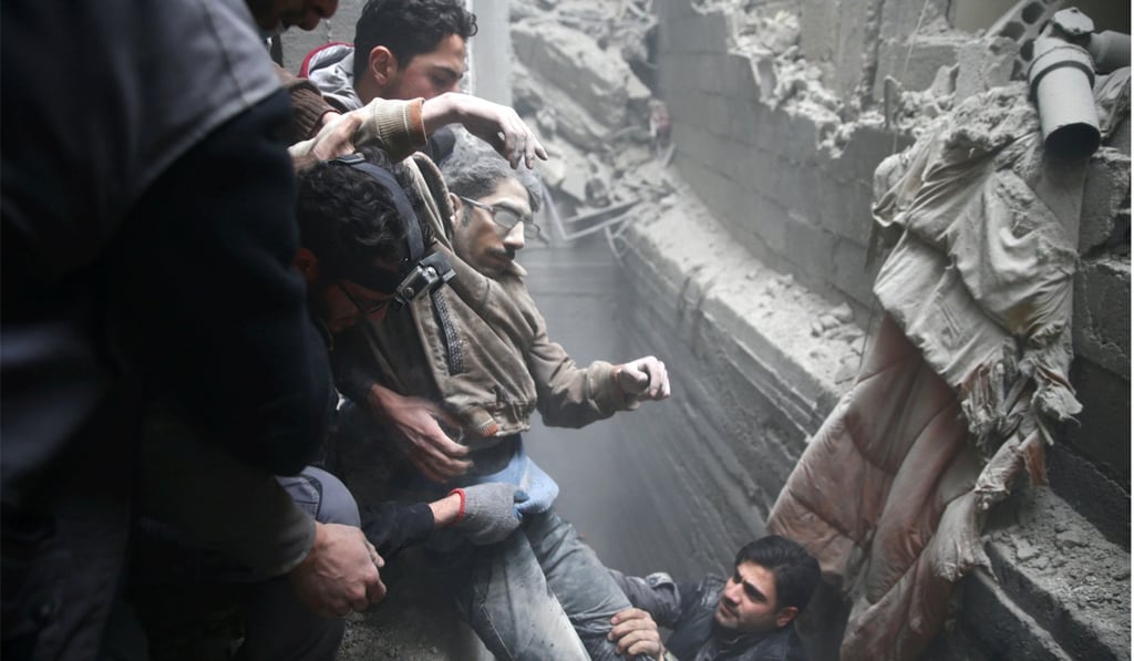 Civil defence help a man from a shelter in the besieged town of Douma on Friday. Photo: Reuters