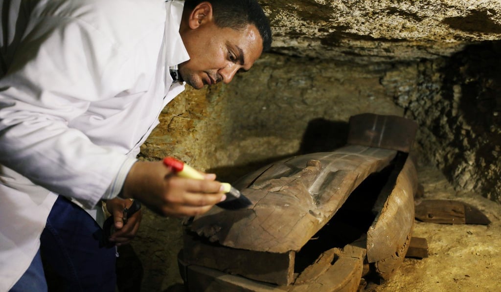 An Egyptian antiquities worker brushes a coffin inside the recently discovered burial site in Minya, Egypt. Photo: Reuters