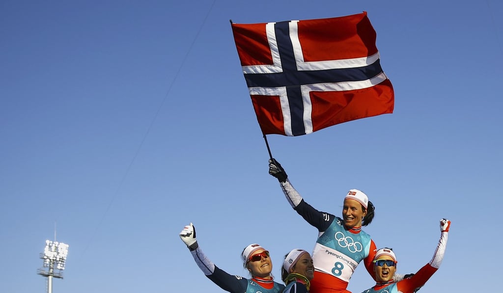 Winner Marit Bjoergen of Norway waves the Norwegian flag as she is carried by her teammates. Photo: Reuters