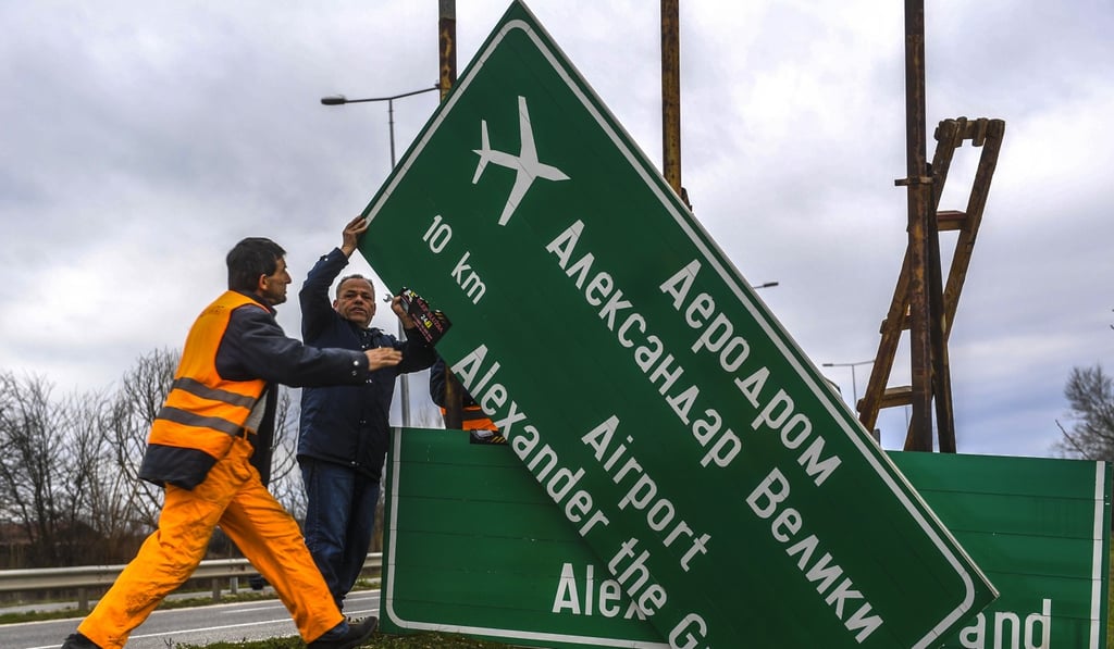 Workers remove a street sign for ‘Skopje Alexander the Great Airport’. Photo: EPA