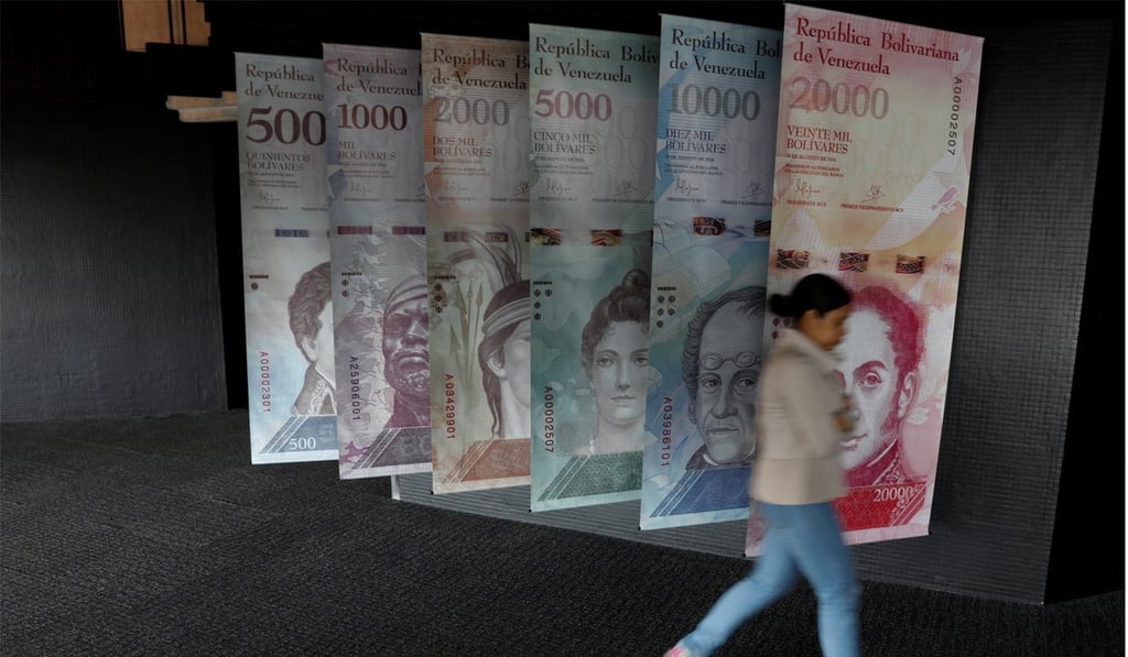 A woman walks by banners of Venezuelan bolivar notes displayed at the Venezuelan Central Bank building in Caracas. Photo: Reuters