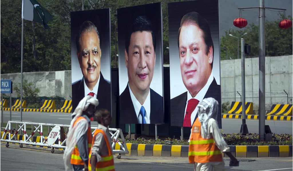 In this April 20, 2015 file photo, municipal workers in Islamabad walk past a billboard showing pictures of Chinese President Xi Jinping, centre, with Pakistan's President Mamnoon Hussain, left, and Prime Minister Nawaz Sharif on display during a two-day visit by Xi to launch an ambitious US$45 billion economic corridor linking Pakistan's port city of Gwadar with western China. Photo: AP