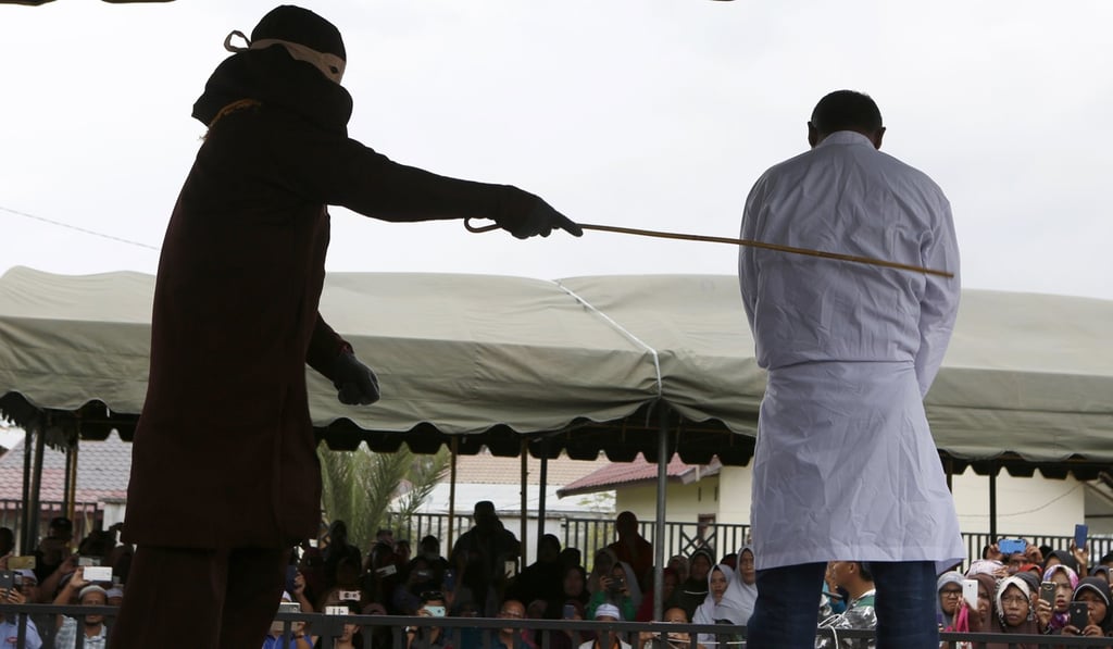 A An Acehnese man is whipped with a cane in front of a public audience for violating sharia law in Banda Aceh. Photo: EPA