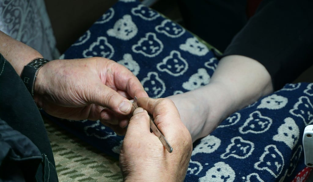 Lam works on the foot of a customer who has an ingrown toenail. Photo: Olivia Chan