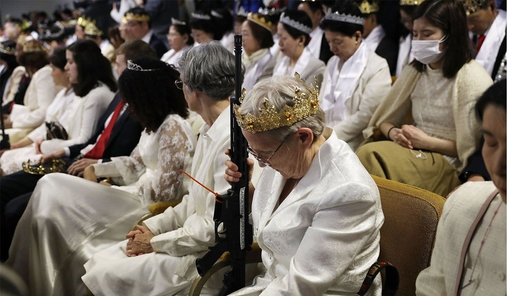 A woman holds an AR-15 rifle during the ceremony. The controversial church, which is led by the son of the late Reverend Sun Myung Moon, believes the AR-15 symbolises the “rod of iron” in the biblical book of Revelation, and it encouraged couples to bring the weapons to a “commitment ceremony” or “Perfection Stage Book of Life Registration Blessing”. Photo: Getty Images via AFP