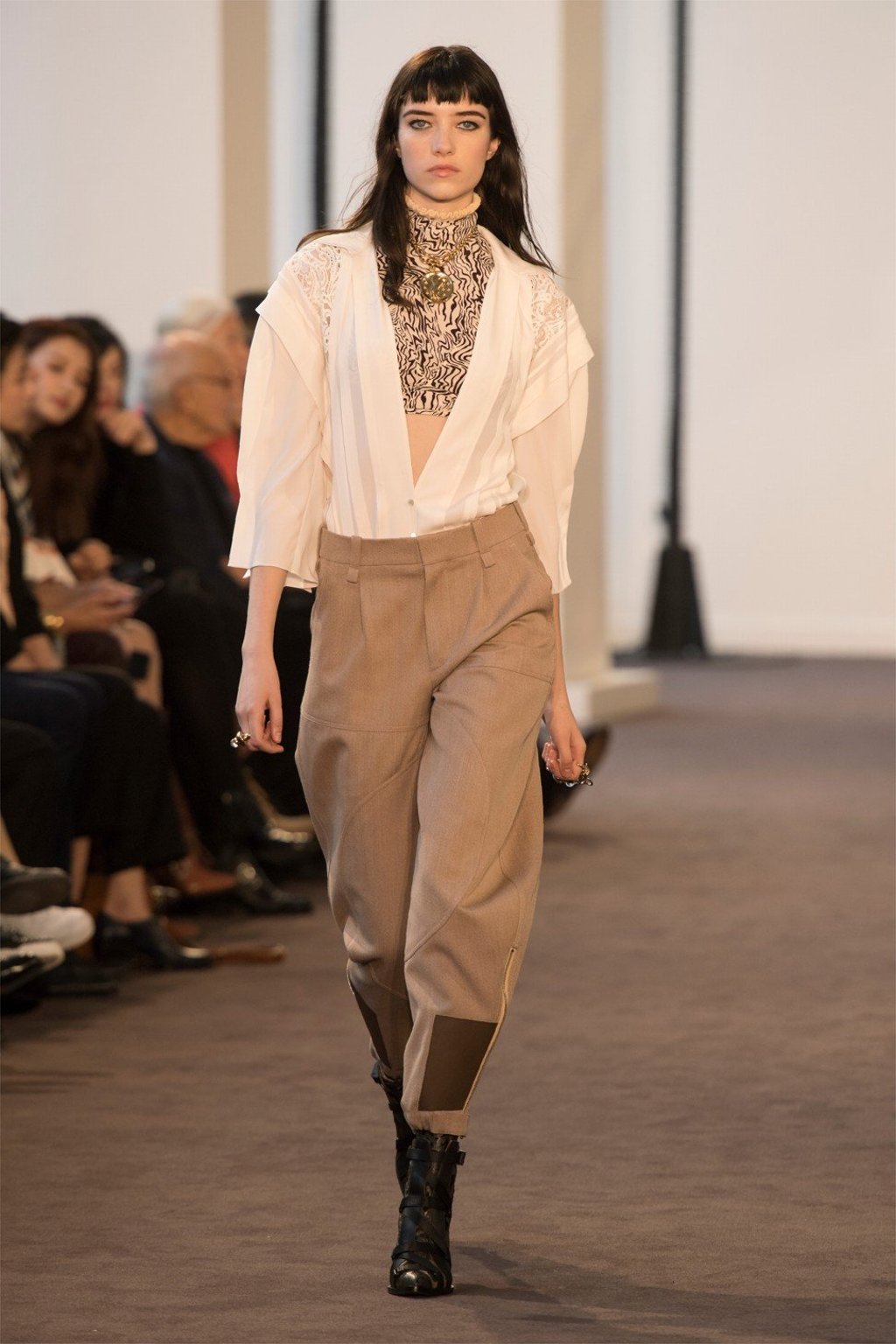 A fluid white shirt with a plunging neckline is paired with a print top, pants with patches and short funky boots.
