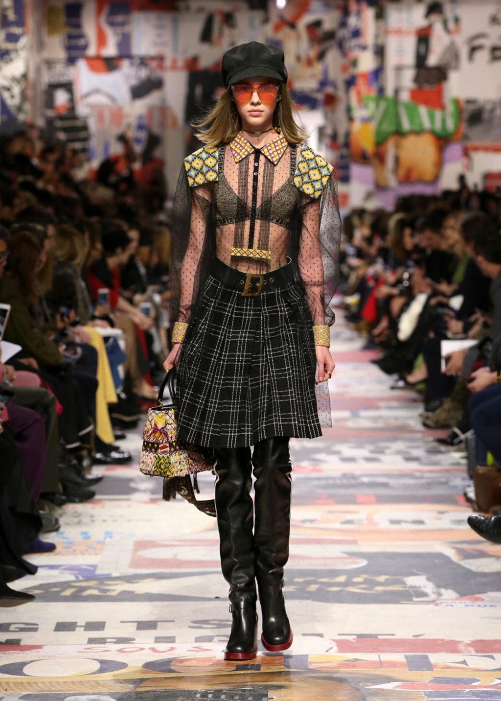 A transparent look with a pleated plaid skirt is paired with long boots.