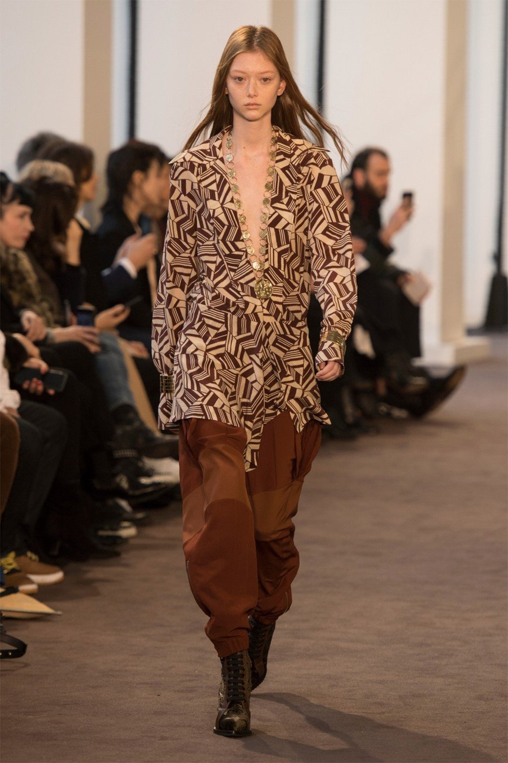 A brown printed shirt is matched with loose brown pants and cool boots.