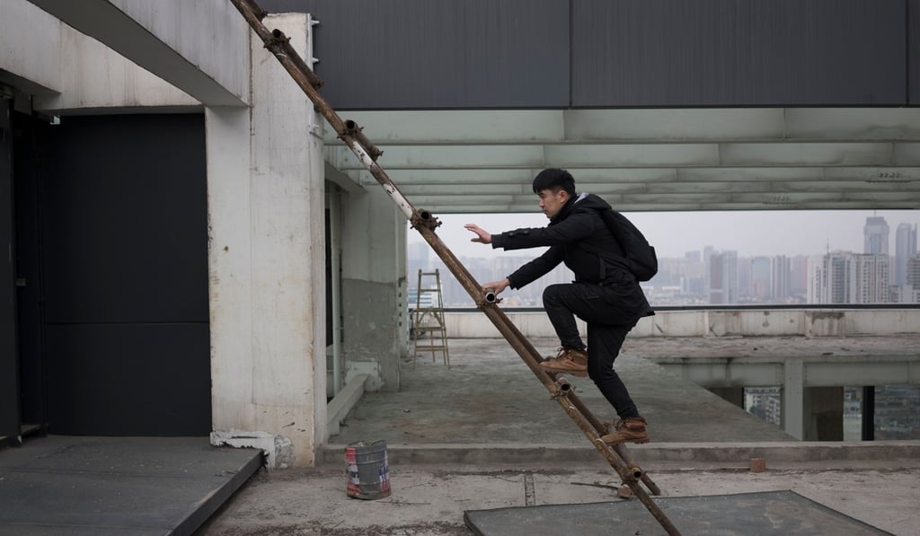 Yan Lei climbs a ladder to reach the rooftop of a building in Chengdu. Photo: AFP Yan Lei climbs a ladder to reach the rooftop of a building in Chengdu. Photo: AFP