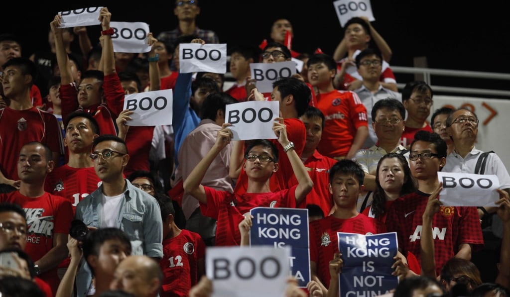 Hong Kong soccer fans hold up signs denouncing the national anthem. Photo: AFP