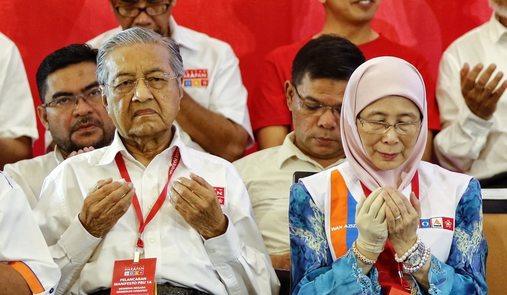 Former Malaysian prime minister Mahathir Mohamad, left, and Wan Azizah, president of the People’s Justice Party, pray in Shah Alam, near Kuala Lumpur. Photo: EPA Former Malaysian prime minister Mahathir Mohamad, left, and Wan Azizah, president of the People’s Justice Party, pray in Shah Alam, near Kuala Lumpur. Photo: EPA