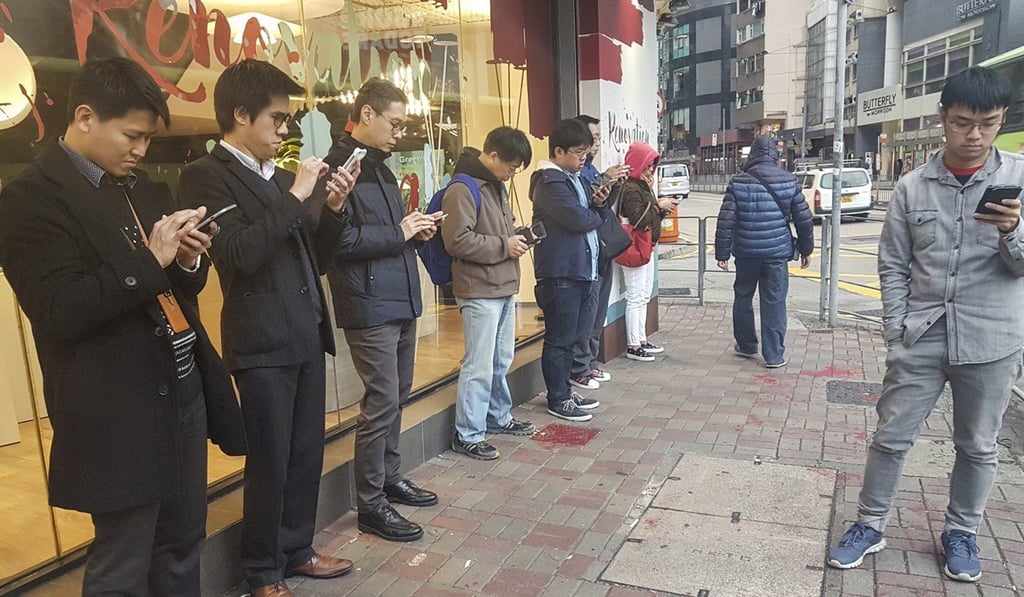 People staring at their mobile phones in Wan Chai. Some doctors believe digital addiction is destroying people’s brains. Photo: Antony Dickson