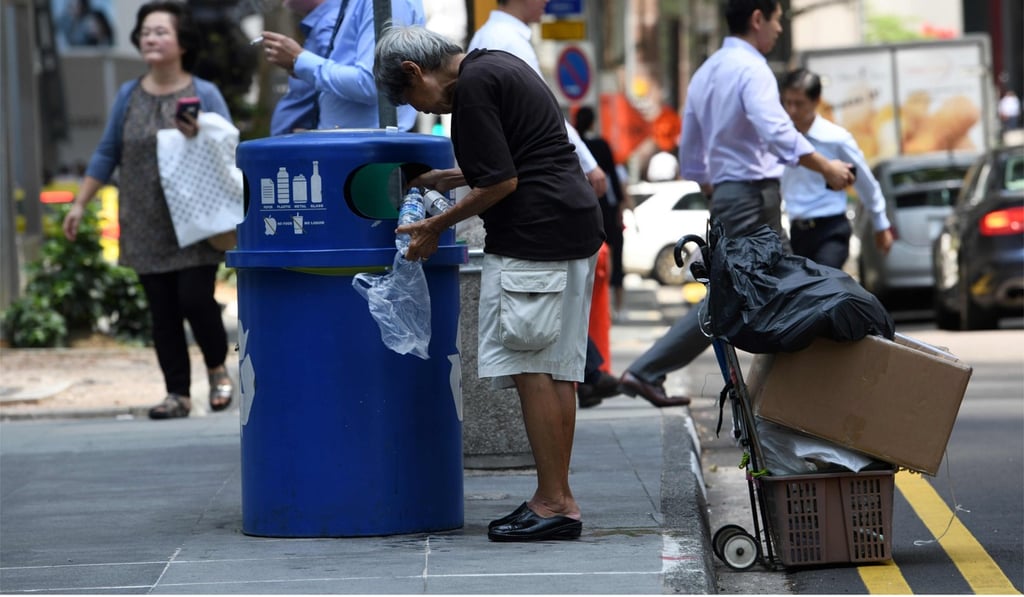 A woman looks for rubbish to recycle from a bin at Raffles Place in Singapore. Photo: AFP A woman looks for rubbish to recycle from a bin at Raffles Place in Singapore. Photo: AFP