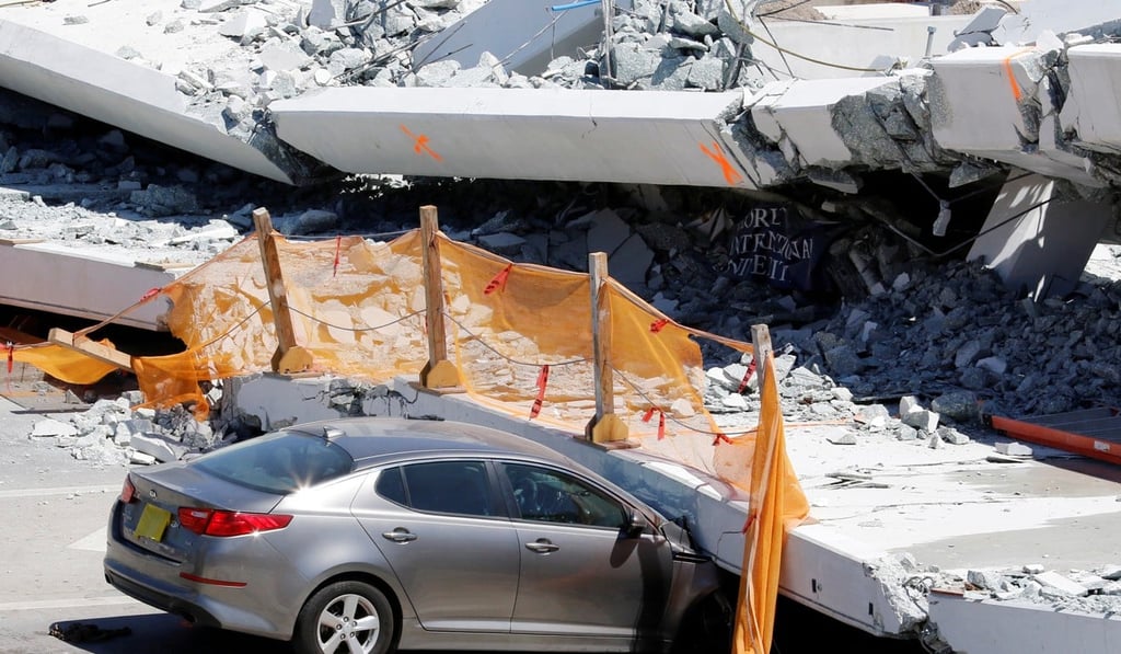 A damaged car is seen partially trapped as workers remove debris from a collapsed pedestrian bridge at Florida International University in Miami, Florida, on March 16, 2018. A survivor has filed a lawsuit against the companies who built the bridge. Photo: Reuters