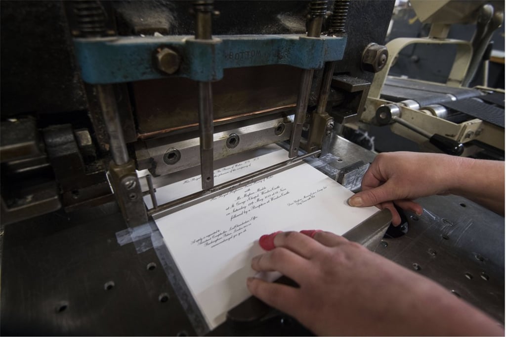 A worker uses the dye stamping press at the workshop of Barnard and Westwood in London, which is printing the invitations for Prince Harry and Meghan Markle's May wedding in London. Photo: EPA