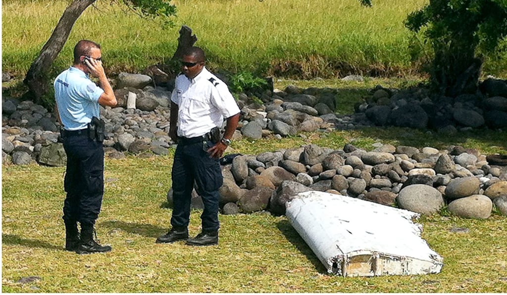 Policemen stand next to a piece of debris from Malaysia Airlines plane MH370 on the French Indian Ocean island of La Reunion. Photo: Agence France-Presse