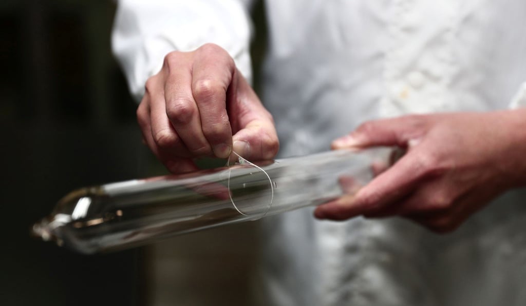 An assistant manager at Sagami Rubber Industries pinches a 0.01mm condom covering a glass cylinder at the company's condom testing facility in Atsugi, Kanagawa prefecture. Photo: AFP An assistant manager at Sagami Rubber Industries pinches a 0.01mm condom covering a glass cylinder at the company's condom testing facility in Atsugi, Kanagawa prefecture. Photo: AFP