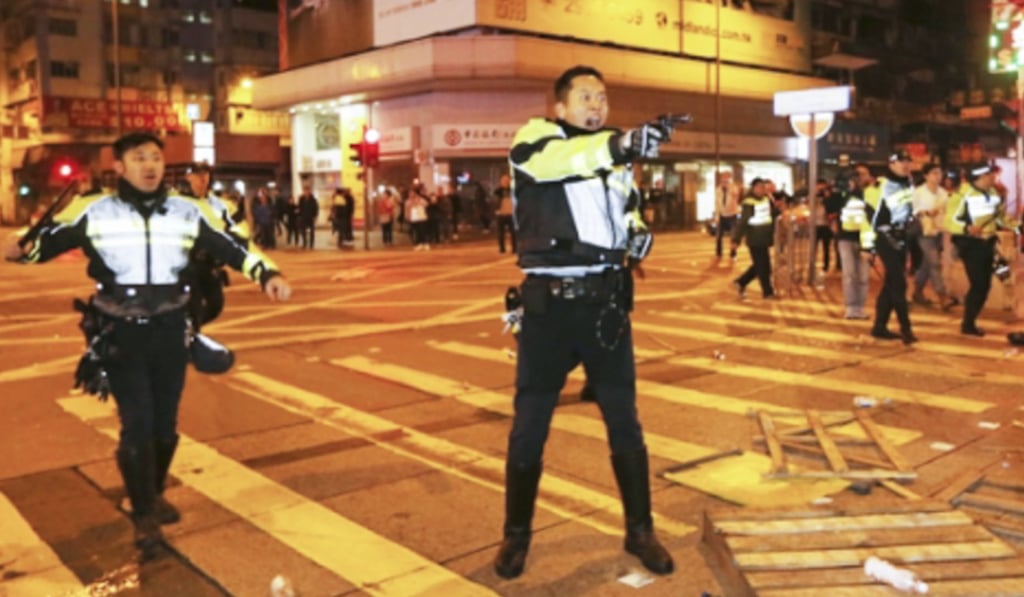 A police officer hold a gun during clash with protesters in Mong Kok, Hong Kong, on February 9, 2016. Decisions by the courts on this matter and others have upset people on both sides of contentious issues. Photo: Handout