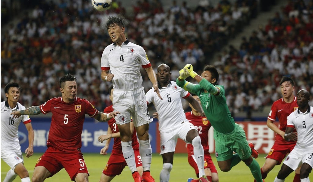 Hong Kong’s Bai He (centre) challenges for a header against China’s tattooed Zhang Linpeng (left). Photo: AP