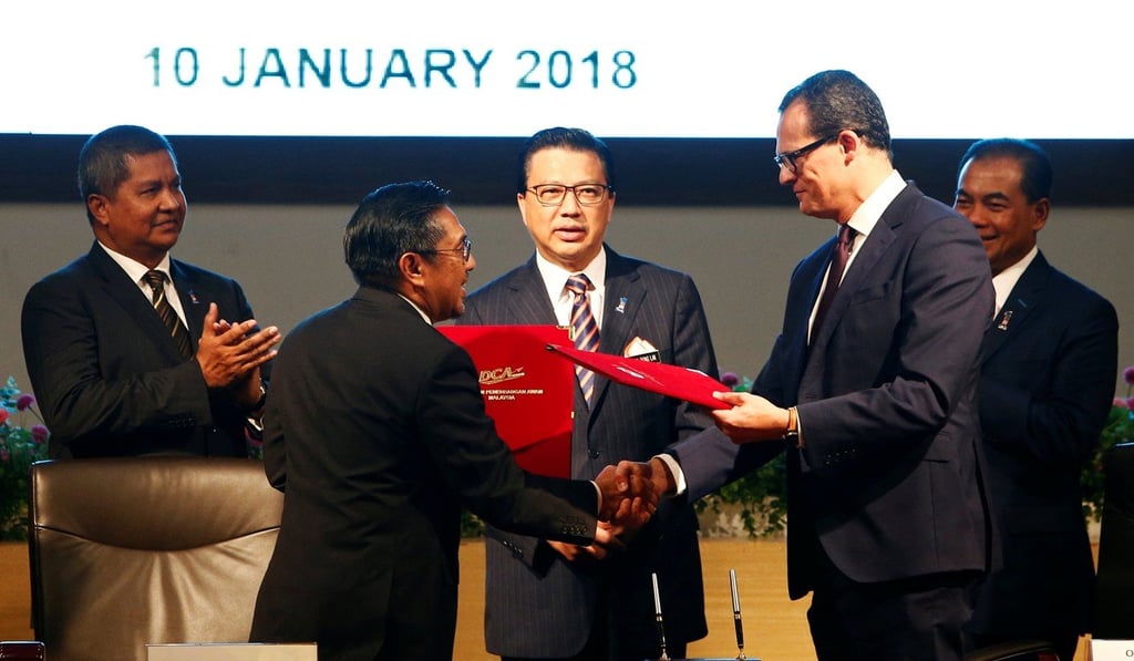 Malaysian civil aviation chief Azharuddin Abdul Rahman (second from left) and Ocean Infinity chief executive Oliver Plunkett (right) exchange documents at the MH370 search operations signing ceremony in Putrajaya, Malaysia. Picture: Reuters