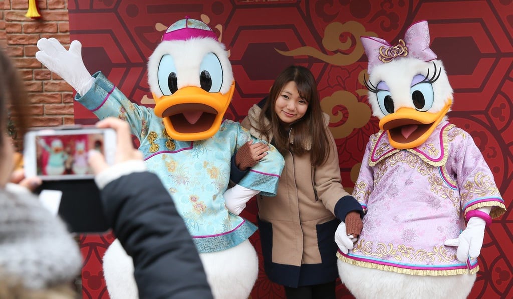 A tourist poses with Disney characters wearing Chinese traditional dress at Shanghai Disney Resort. Photo: Xinhua
