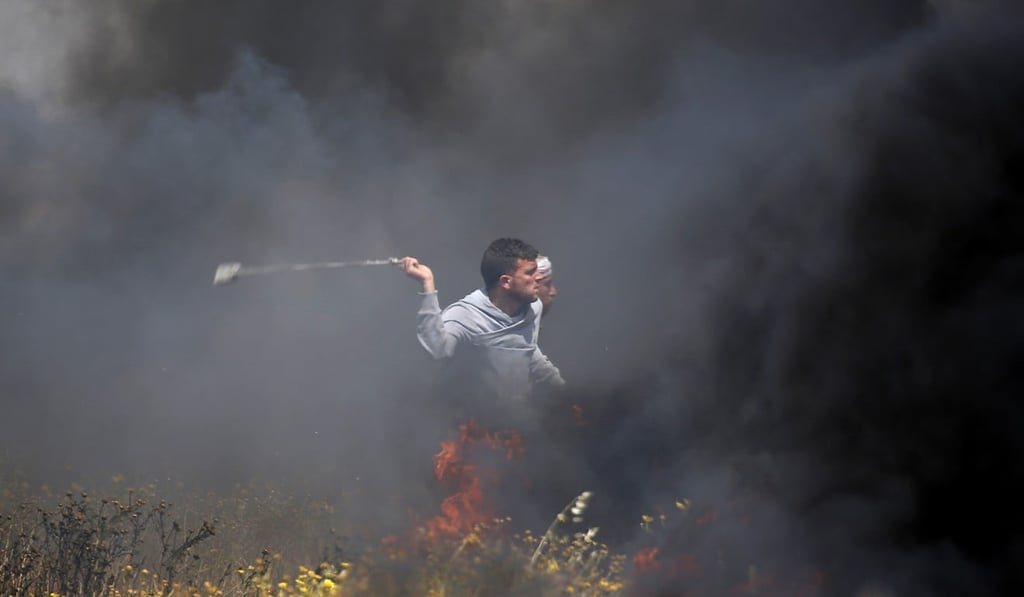 A Palestinian protester slings stones towards Israeli soldiers during clashes with Israeli troops along the Gaza Strip border with Israel on Friday. Photo: AP A Palestinian protester slings stones towards Israeli soldiers during clashes with Israeli troops along the Gaza Strip border with Israel on Friday. Photo: AP