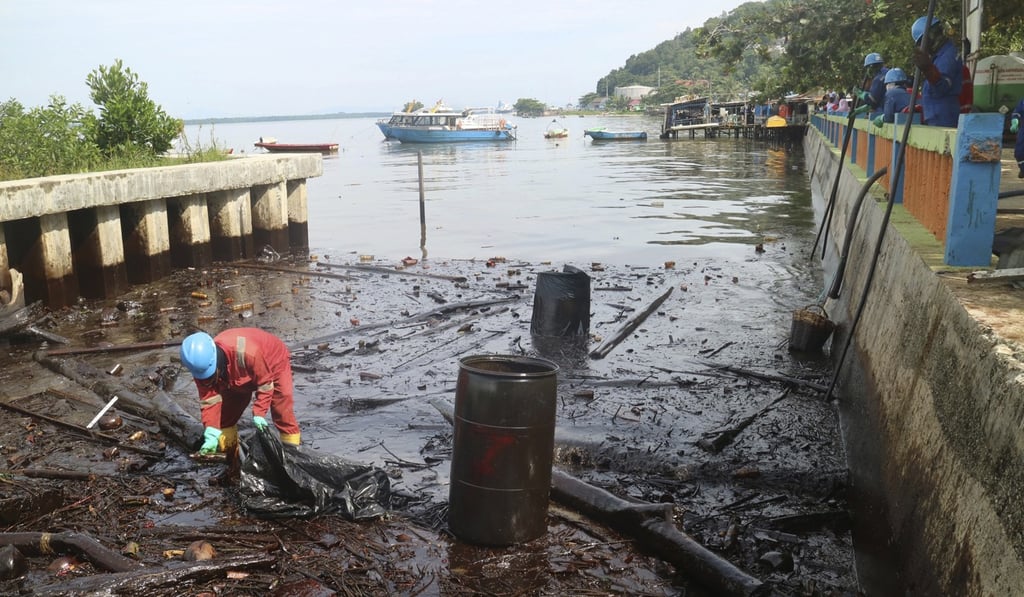 A worker cleans up oil that inundated the coastline in Balikpapan. Photo: AP A worker cleans up oil that inundated the coastline in Balikpapan. Photo: AP