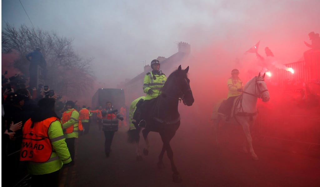 Police officers clear the road as Liverpool fans set off flares to welcome the Manchester City team bus. Photo: Reuters