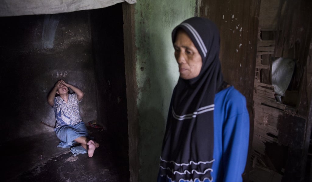 Abtyah outside the storeroom where her daughter, Ernawati, is chained up, on the outskirts of Sukabumi, West Java, Indonesia. Picture: Miguel Candela Abtyah outside the storeroom where her daughter, Ernawati, is chained up, on the outskirts of Sukabumi, West Java, Indonesia. Picture: Miguel Candela