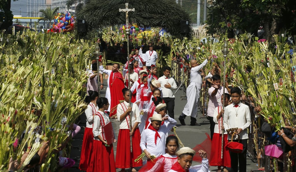 Roman Catholic priests bless with holy water palm frond-waving devotees in observance of Palm Sunday at Baclaran church in suburban Paranaque city, southeast of Manila, Philippines. Photo: AP