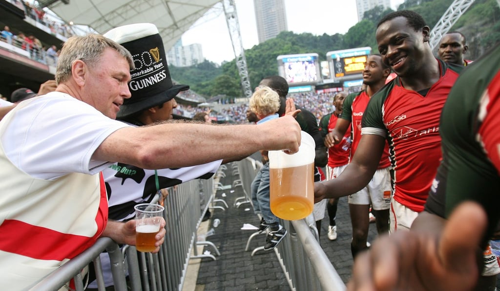 Kenya's Innocent Simiyu takes a beer from a fan beside the pitch. Photo: Nora Tam