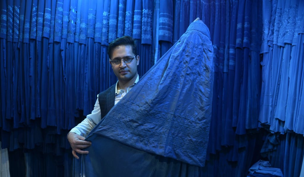 An Afghan shopkeeper showing a Chinese-made imported burqa at his shop in Mazar-i-Sharif. Photo: AFP