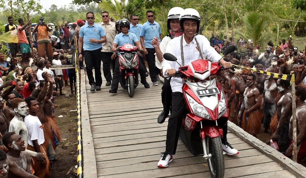 Indonesia President Joko Widodo, with his wife Iriana, drives an electric motorbike during a visit to Agats district in Asmat, Papua province, Indonesia. Photo: Reuters
