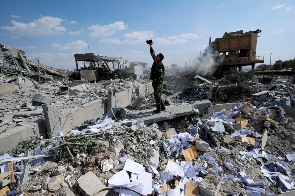A Syrian soldier films the damage of the Syrian Scientific Research Center which was attacked by US, British and French military strikes to punish President Bashar Assad for suspected chemical attack against civilians, in Barzeh, near Damascus, Syria on Saturday. Photo: AP