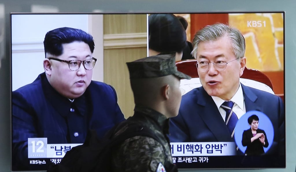 A South Korean marine passes a screen showing Kim Jong-un and Moon Jae-in. Photo: AP