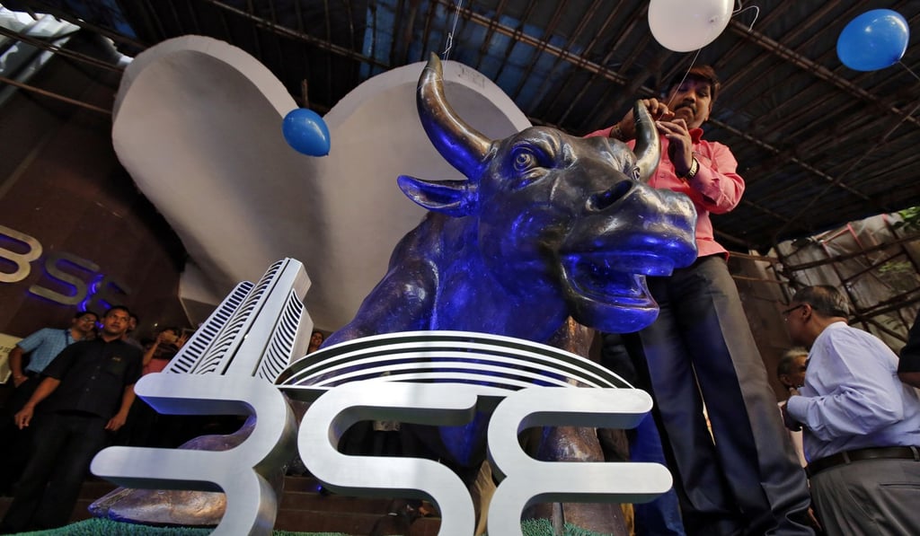 A man ties a balloon to the horns of a bull statue at the entrance of the Bombay Stock Exchange as part of celebrations of the Sensex index rising to over 30,000 points in Mumbai, India, in April 2017. The deepening of financial services in India, including the rapid adoption of mobile banking, has helped Indian banking stocks accrue value. Photo: Reuters