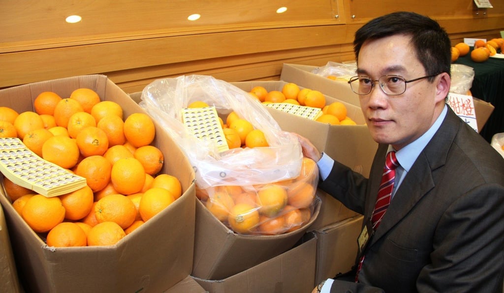 Lam Yau-tak, divisional commander of the Intellectual Property General Investigation unit from Hong Kong Customs poses with the counterfeit Sunkist oranges. Photo: SCMP