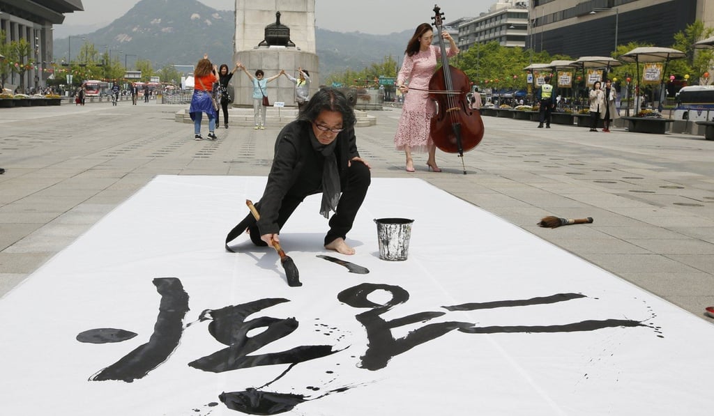 A calligraphist in Seoul writes “Peace is spring, flowers” to celebrate the summit between South Korean President Moon Jae-in and North Korean leader Kim Jong-un. Photo: EPA