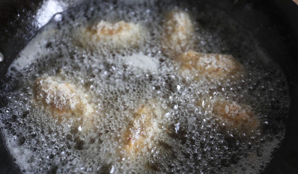 The croquettes frying in oil.