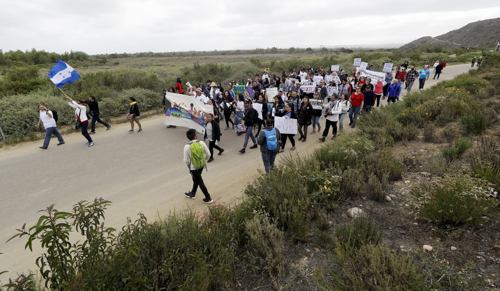 Demonstrators in San Diego march to meet Central American migrants travelling in a caravan for a gathering at the border on the beach where the border wall ends in the ocean on Sunday. Photo: AP Demonstrators in San Diego march to meet Central American migrants travelling in a caravan for a gathering at the border on the beach where the border wall ends in the ocean on Sunday. Photo: AP