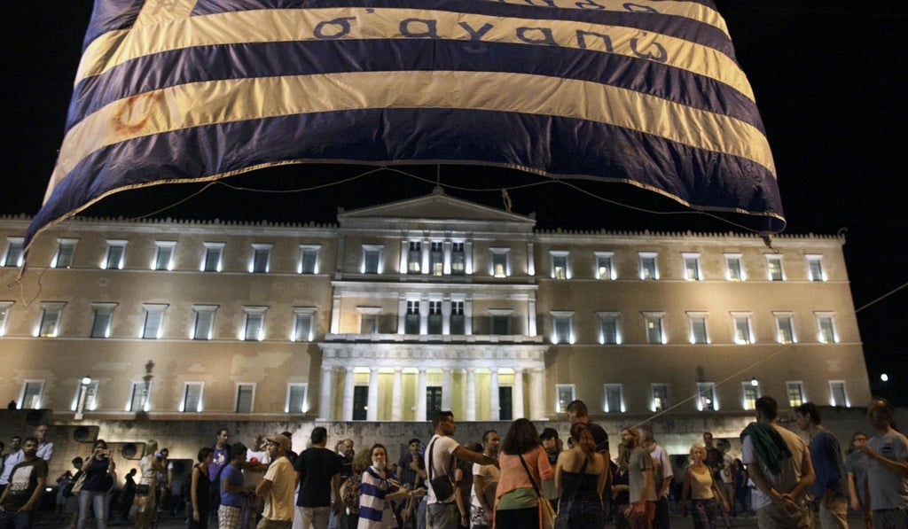 Anti-austerity protesters lift a Greek flag in front of the Greek Parliament in Athens in 2015 as Prime Minister Alexis Tsipras battled to win legislative approval for a bailout deal to keep Greece in the euro. Three years later, the IMF, Greece and European creditors have still not agreed on how to reduce the country's debt burden. Photo: Reuters