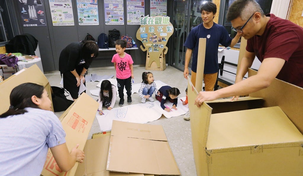 Parents and their children make a slide out of cardboard at a workshop. Photo: Dickson Lee