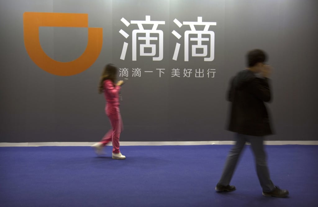 Members of the public walk past a sign for Chinese ride-hailing service Didi Chuxing. Photo: AP