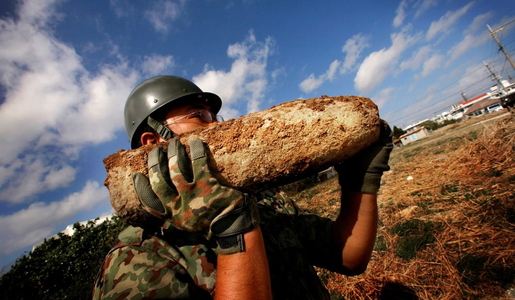 A member of the Japan Ground Self Defence Force carries unexploded ordnance in Okinawa, Japan. Photo: AP