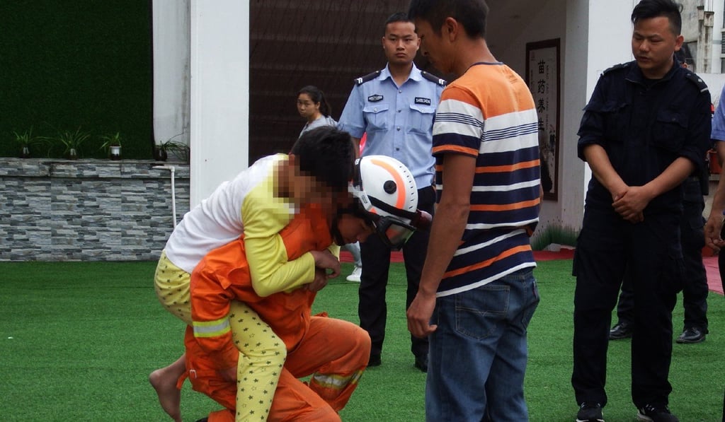 The boy arrives on the ground as a police officer looks on. Photo: Weibo