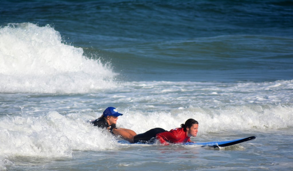Surfing instructor teaches a woman how to surf in Surfers Paradise, Queensland, Australia. Photo: Alamy