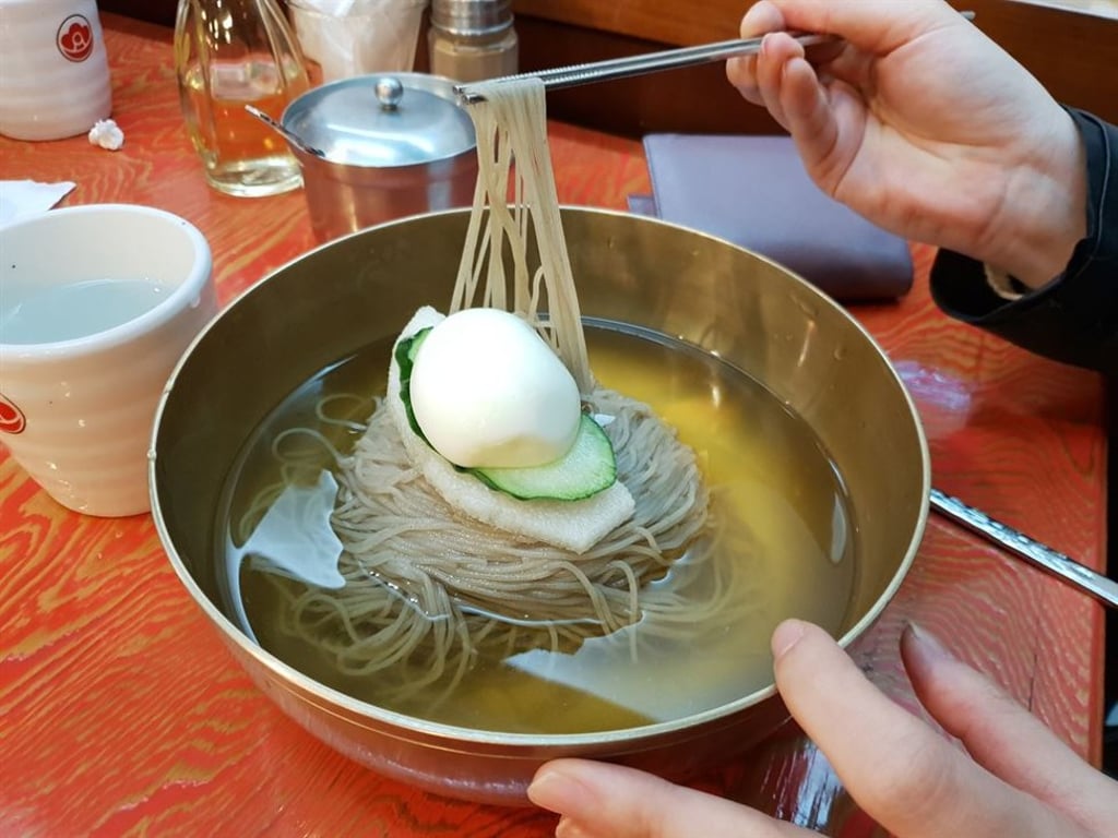 A Korea Times staff member tries Pyongyang naengmyeon at a restaurant in Jung-gu, central Seoul. The noodles are made with buckwheat. In South Korea, cold noodles are served in a clear beef broth. Photo: Korea Times A Korea Times staff member tries Pyongyang naengmyeon at a restaurant in Jung-gu, central Seoul. The noodles are made with buckwheat. In South Korea, cold noodles are served in a clear beef broth. Photo: Korea Times