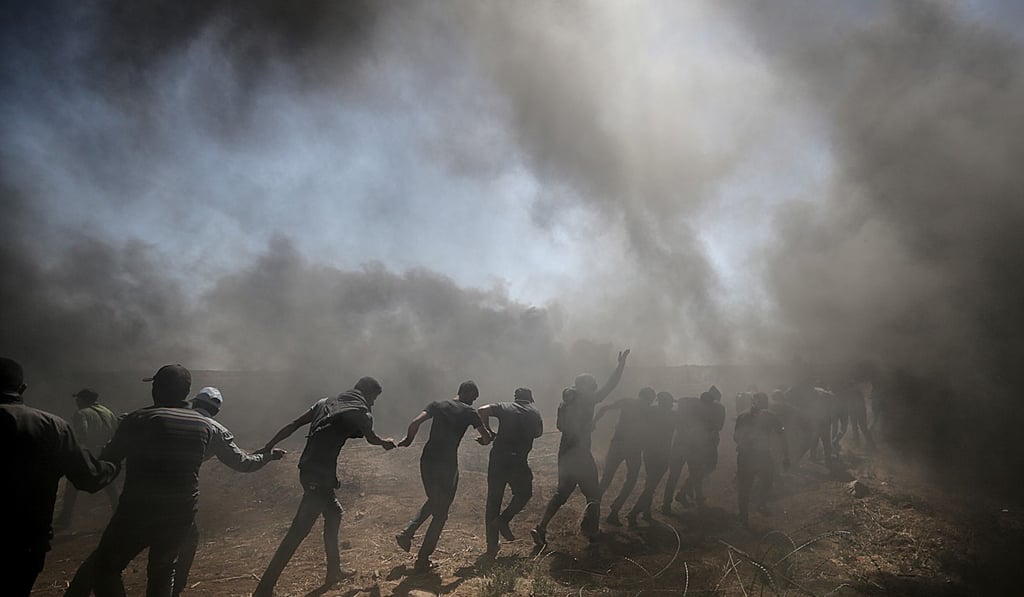 Palestinians protesters pull wire fence installed by Israeli troops along the border during clashes Monday. Photo: EPA Palestinians protesters pull wire fence installed by Israeli troops along the border during clashes Monday. Photo: EPA